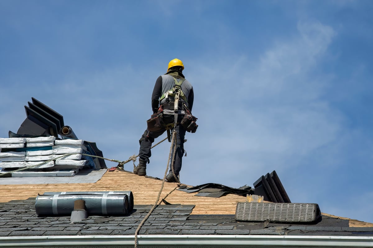 Worker applying roofing materials with nail gun